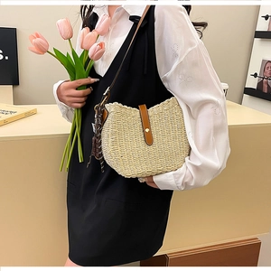 Detail of woven straw shoulder bag with leather strap and decorative chocolate charm