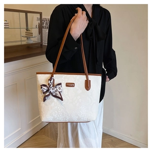 Detail view of large white snakeskin tote bag with brown leather straps and a silk scarf