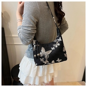Close-up of black shoulder bag with shiny silver butterfly sequins and slim strap