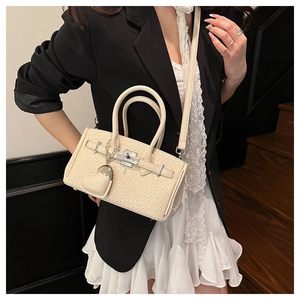 Detail of cream beige crocodile pattern leather bag with metal lock and heart charm