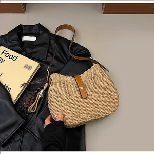 Detailed close-up of woven straw texture with brown leather strap and button closure