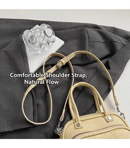 Detail view of beige lychee texture handbag with round handle and adjustable shoulder strap