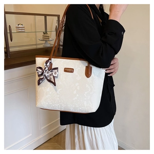 Detail of white snake pattern tote bag featuring brown leather trim and floral silk scarf