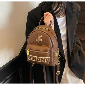 Détail de la broderie d'ours mignon et fermeture éclair dorée sur sac à dos marron