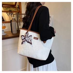 Detail of cream snake pattern tote bag with brown leather straps and paisley silk scarf
