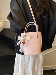 Sac seau rose en cuir PU avec breloque cerise et nœud, présenté dans une vue latérale