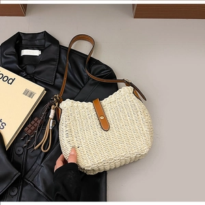 Detail of woven straw bucket bag with brown leather strap and chocolate charm decor