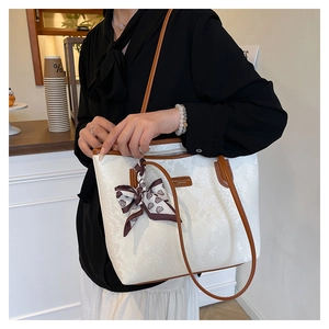 Detail of snake skin texture tote bag with brown leather trim and heart print silk scarf