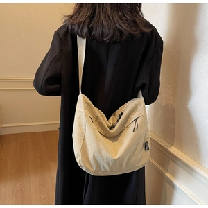 Dettaglio di una grande borsa a tracolla in tela beige con tasca a zip ed etichetta