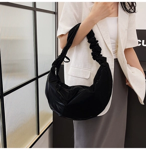 Close-up of black crescent shoulder bag featuring stylish ruched strap detail