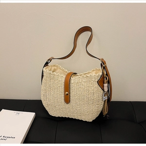 Detail of hand-woven straw hobo bag with adjustable brown leather strap and tassel