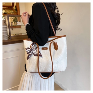 Detailed texture of white snakeskin tote bag with brown straps and silk scarf accent
