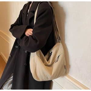 Dettaglio della tracolla regolabile e della texture in tela della borsa a tracolla beige
