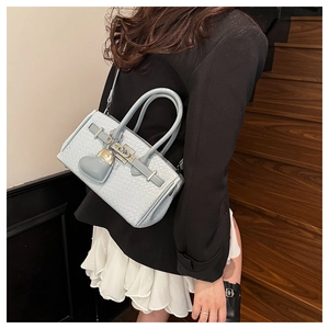 Detail of light blue woven Kelly handbag with heart charm and silver metal clasp