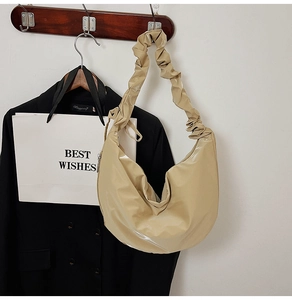 Detail of beige patent leather hobo bag with trendy ruched shoulder strap design