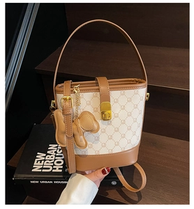 Détail du sac seau en toile avec finitions cuir, fermoir métal et breloque noeud