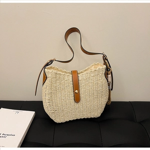 Detail of woven straw bag with brown leather trim and metallic buckle closure