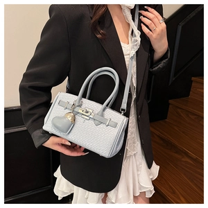 Detail of light blue textured handbag with silver twist lock and heart charm