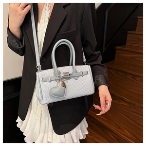 Detail shot of ice blue woven texture Kelly bag with silver swivel lock and heart charm