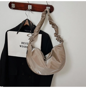 Detail view of khaki pleated shoulder bag strap with glossy texture on a blazer