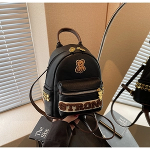 Détail de l'écusson ours et des clous dorés sur le sac à dos en cuir noir