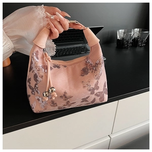Detail of pink sequin handbag featuring silver butterfly patterns and a metal ball charm