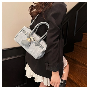 Detailed view of light blue woven texture with silver lock and heart leather charm