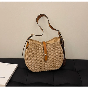 Detail of woven straw shoulder bag with brown leather trim and chocolate charm