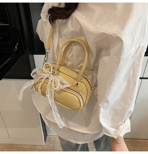 Close-up of yellow pebbled leather mini bag with elegant white lace bow and pearl charm