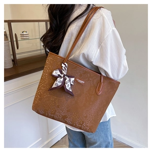 Close-up of brown snakeskin embossed tote bag featuring a decorative silk scarf