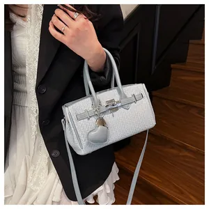 Detail of light blue woven texture handbag with silver lock and heart charm