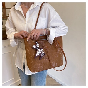 Detail of brown snakeskin embossed tote bag with decorative scarf and metal logo