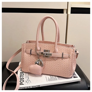 Detail of pink woven leather texture handbag with silver metal buckle and heart pendant