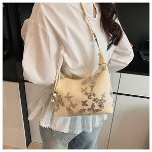 Detail of beige sequin butterfly embroidery on stylish shoulder bag with metal ball zipper