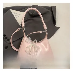 Sac rose avec poignée tressée orné de nœuds en dentelle et de breloques en perles
