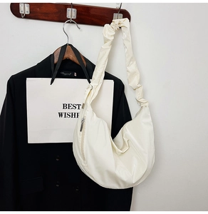 Detail of cream white pleated shoulder strap on a hobo bag with a stylish metal zipper