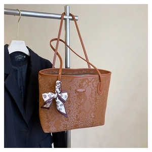 Brown snakeskin tote bag with silk scarf detail hanging next to a black blazer