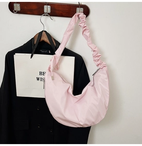 Detail of pink pleated strap and glossy crescent shoulder bag with silver zipper