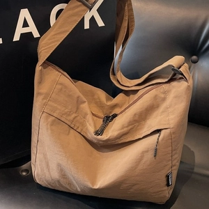 Borsa a tracolla minimalista in nylon kaki con tracolla larga su divano nero