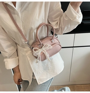 Detailed shot of pink crossbody bag with white lace bow and pearl embellishment