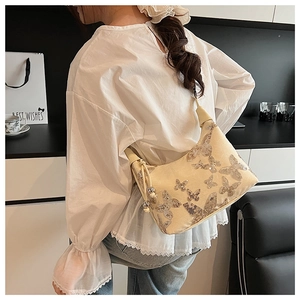 Close-up of a cream shoulder bag featuring sparkling silver sequin butterfly embroidery