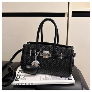 Detailed view of black woven texture leather handbag with heart charm on fashion magazine