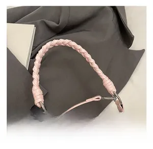 Détail de la poignée en cuir tressé rose avec boucles métalliques argentées sur un sac