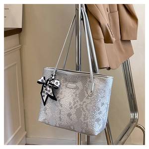 Detail of silver snake-pattern tote bag featuring a black and white polka dot silk scarf