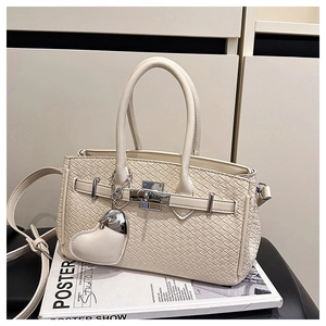 Close-up of cream woven handbag featuring silver twist lock and heart leather charm