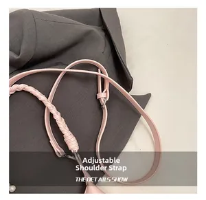 Détail de la bandoulière réglable en cuir rose avec texture tressée et boucle en métal