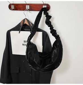 Detail of black satin crescent bag with elegant pleated scrunchie shoulder strap