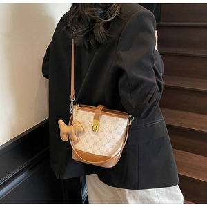 Détail du sac seau bicolore avec imprimé monogramme et breloque chien en cuir mignon