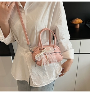 Pink lychee grain crossbody bag with pearl lace bow detail worn by female model