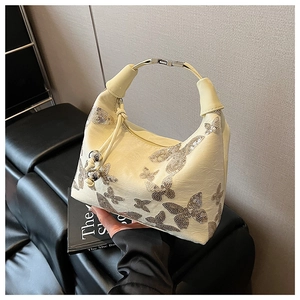 Detail of cream leather shoulder bag featuring sequin butterfly embroidery and metallic handle
